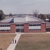 Three people standing in front of gymnasium building.